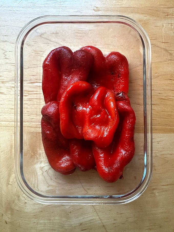 Homemade roasted red peppers in a storage vessel.