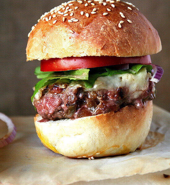 A pan-seared burger with secret sauce, pickled onions, and tomato on homemade brioche.