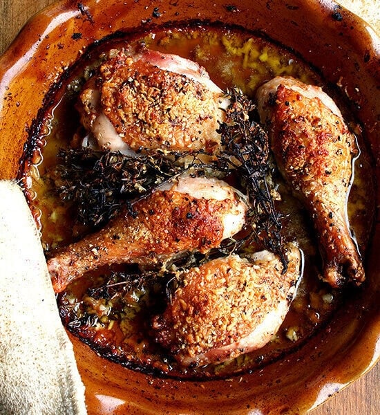 An overhead shot of a pie plate with roast chicken in white wine, olive oil, and parmesan.