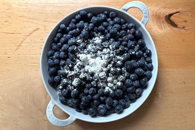 A gratin dish filled with blueberries topped with a tablespoon of cornstarch.