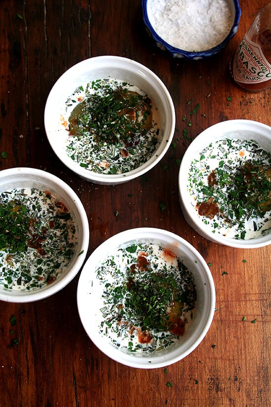 4 ramekins, each holding an egg, cream, herbs and tabasco