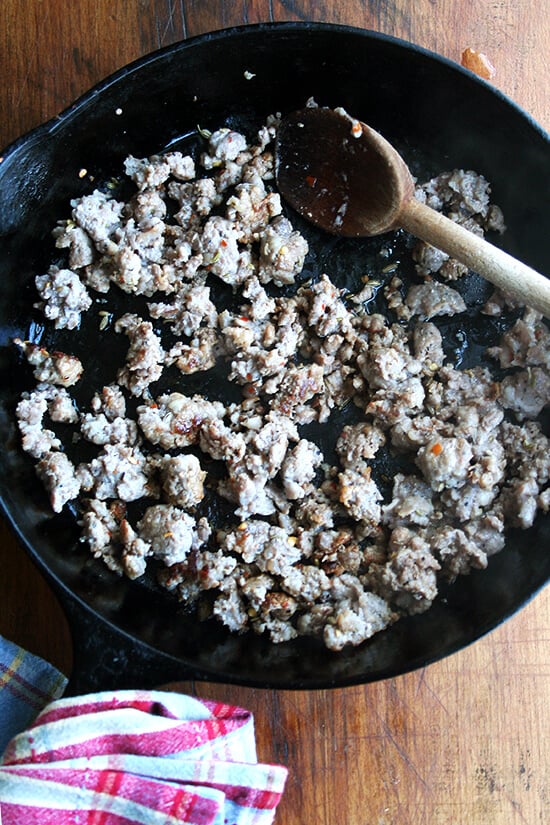 A cast iron skilled browning hot Italian sausage.