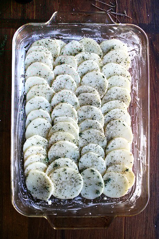Layer of potatoes in baking dish seasoned with salt, pepper and thyme. 