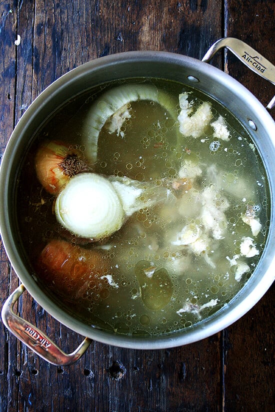 A stock pot filled with onions and chicken scraps.