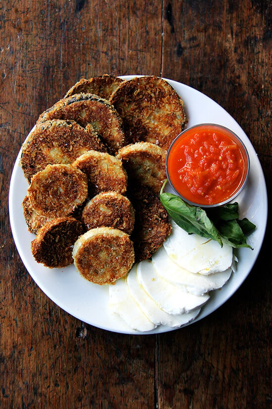 These crispy rounds of eggplant parmesan are irresistible, and with a few slices of cheese, some bread, sauce, maybe some prosciutto or other cured meats, you can make a meal out of them. Little ones, teary eyed or otherwise, seem to like them, too. // alexandracooks.com A plate of crispy eggplant rounds.