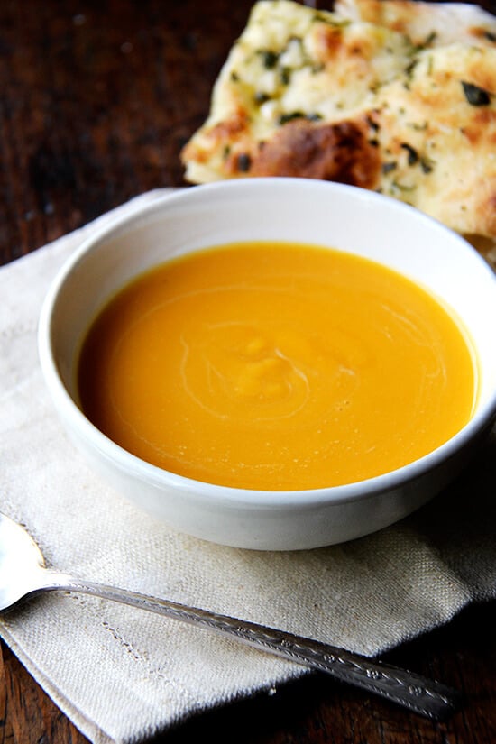 This butternut squash soup comes together in a flash and couldn't taste more like fall, the fragrant herbs so nicely complementing the squash and the subtle sweetness of the apple, the tangy sour cream balancing it all out. I've been serving it with flatbread topped with olive oil, sea salt, and minced sage and rosemary, two of butternut squash's best pals. // alexandracooks.com A bowl of butternut squash and cider soup with a spoon.