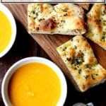 Butternut squash soup in bowls aside herbed flatbreads.
