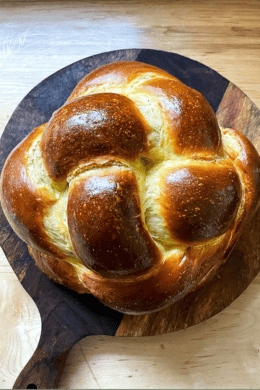 A loaf of challah on a circular cutting board.