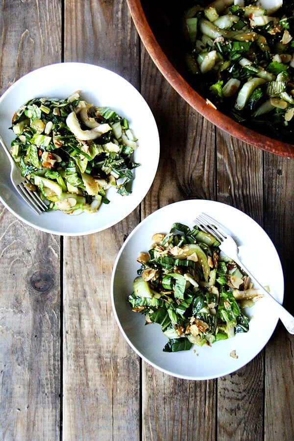 Bok choy salad is excellent as its crunchy stalks and sturdy leaves are capable of enduring a bold, salty-sweet dressing. A slightly sweet dressing, in fact, is just what slightly bitter bok choy needs. The most fun part about this recipe, however, is the sesame-almond crunch, a mix of melted sugar, toasted almonds and sesame seeds, that comes together in a flash and disappears about as quickly. // alexandracooks.com Bok choy salad in two salad bowls.