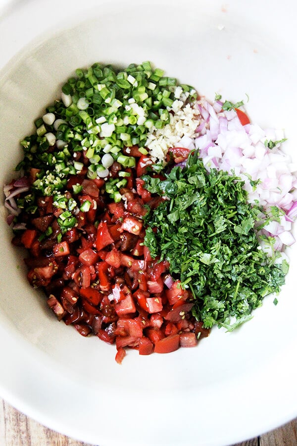 I love that this tomato salsa uses both fresh lime juice and vinegar. I love the inclusion of toasted cumin seeds, which adds a subtle smokiness and reminds me of eating papadums. I love the touch of oil to balance out all of the acid. // alexandracooks.com Tomato salsa ingredients in a large bowl.