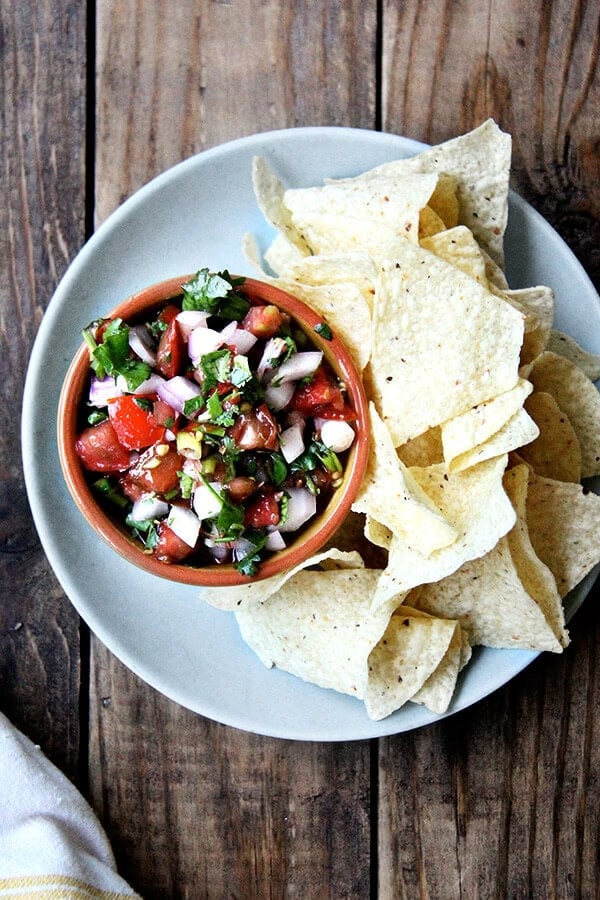 I love that this tomato salsa uses both fresh lime juice and vinegar. I love the inclusion of toasted cumin seeds, which adds a subtle smokiness and reminds me of eating papadums. I love the touch of oil to balance out all of the acid. // alexandracooks.com A platter of Moosewood tomato salsa aside chips.