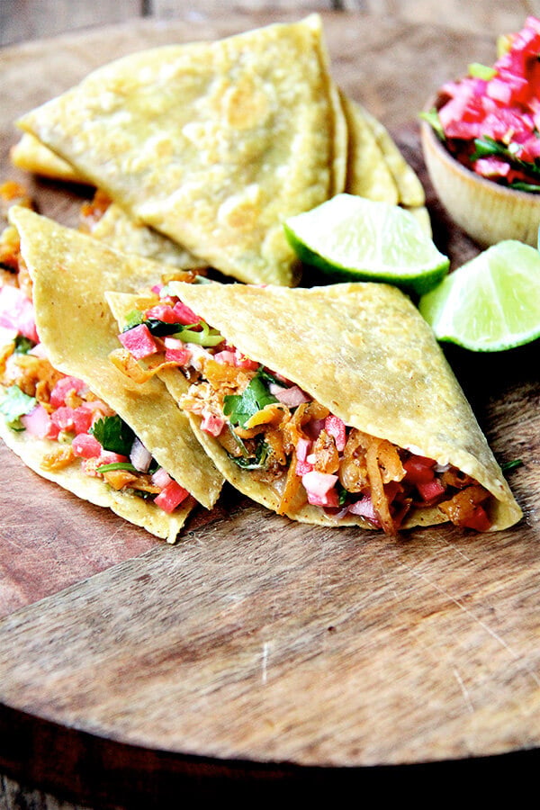 Friends, these sweet potato quesadillas have become one of my favorite things to eat. The filling, a mix of sautéed onions, grated sweet potatoes and spices (cumin, oregano, cayenne, and chili powder), comes together quickly with the help of a food processor's shredder attachment and keeps well in the fridge, making for quick preparation at the dinner hour. // alexandracooks.com sweet potato quesadillas on a board.