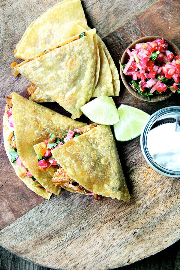 Friends, these sweet potato quesadillas have become one of my favorite things to eat. The filling, a mix of sautéed onions, grated sweet potatoes and spices (cumin, oregano, cayenne, and chili powder), comes together quickly with the help of a food processor's shredder attachment and keeps well in the fridge, making for quick preparation at the dinner hour. // alexandracooks.com Sweet potato quesadillas on a board.