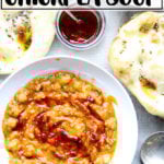 Moroccan chickpea stew, aka Leblebi, on a table with bread and harissa.