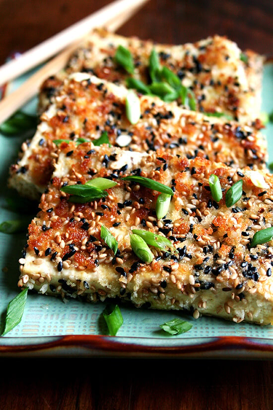 This baked tofu has a simple preparation, which calls for making a four-ingredient dressing, and results in nicely textured and completely tasty tofu—crispy edges, custardy centers, sesame-soy flavor throughout. // alexandracooks.com Sesame-crusted tofu on a platter.