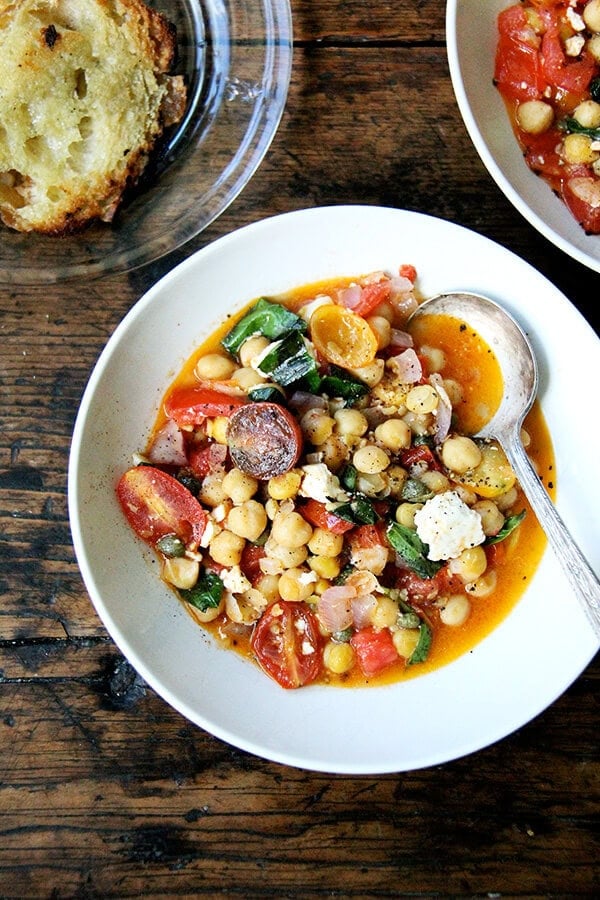 These stewy chickpeas are a mix of chickpeas, tomatoes, basil, and feta. After I made it the first time, we devoured most if it immediately with crusty, olive oil-toasted bread, then snacked on the leftovers for days. // alexandracooks.com A bowl of stewy chickpeas with tomatoes and feta.