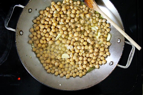 A sauté pan with chickpeas, garlic, and olive oil.