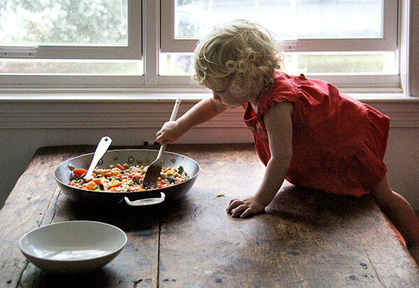Tig stirring the stewy chickpeas on a table.