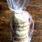 A stack of vanilla bean sablé cookies tucked in a cellophane bag, tied with baker's twine.