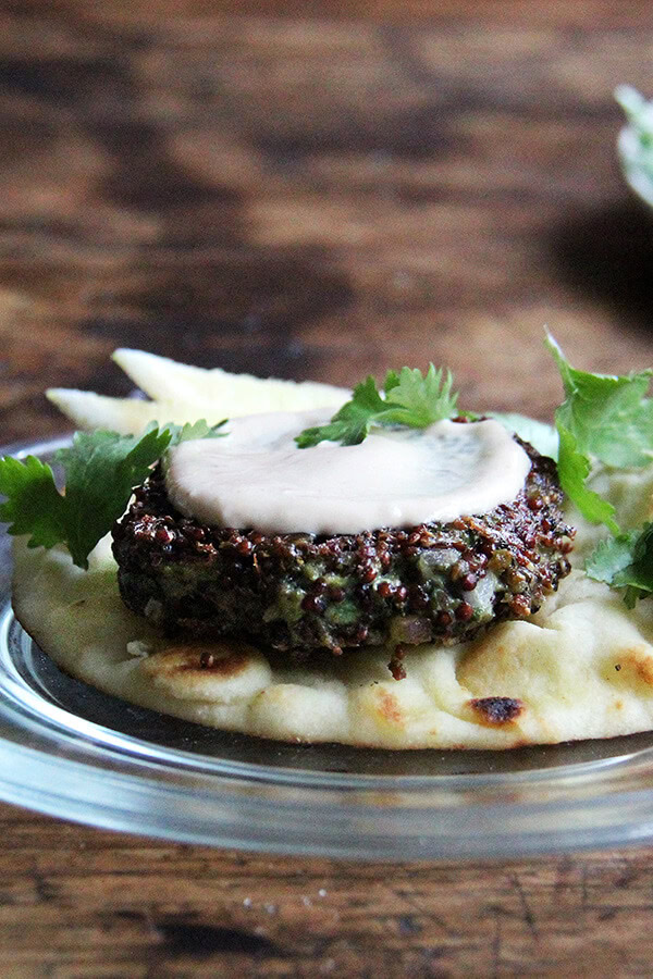 This crispy quinoa cakes can be adapted endlessly—use chard, kale, broccoli rabe, etc. in place of the mustard greens. I like serving them with naan and a yogurt-tahini sauce. The cooked patties are so nice to have on hand—I find myself snacking on them all day—and the "batter" can be prepared ahead of time, stored in the fridge, and baked or fried as needed. // alexandracooks.com A plate topped with a crispy quinoa cake.