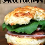 A biscuit sandwich of ham, arugula, and mustard sauce.