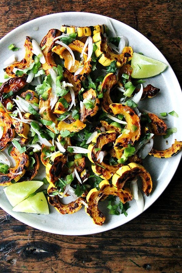 Roasted delicata squash, if you are unfamiliar, is one of the easiest of all the squashes to prepare. You can cut through its skin easily with a knife, and you can eat the skin once roasted—it's truly delicious. Here, a tart dressing, made with shallots and jalapeños macerated in lime juice, so nicely complements the sweet squash, and a showering of cilantro at the end offers a blast of freshness. // alexandracooks.com Roasted delicata squash with chilies, lime, and cilantro.