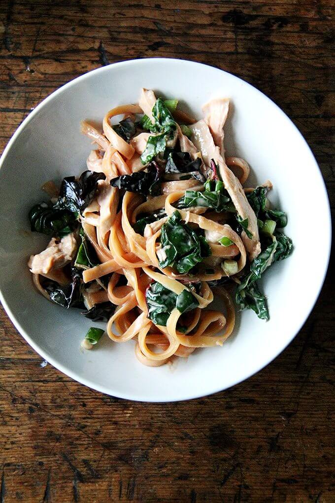 This is one of the easiest, tastiest, most genius recipes I've made in a long time: you drop a chicken breast into boiling water, cover the pan, then let it sit for 15 minutes off the heat. In the meantime, you make a sauce from all pantry ingredients — including both tahini and sesame oil for big sesame flavor — then you retrieve the chicken breast, cook sesame noodles in the now seasoned broth, and when they're done, you toss it all together. That's it! // alexandracooks.com A bowl of sesame noodles with Swiss chard.