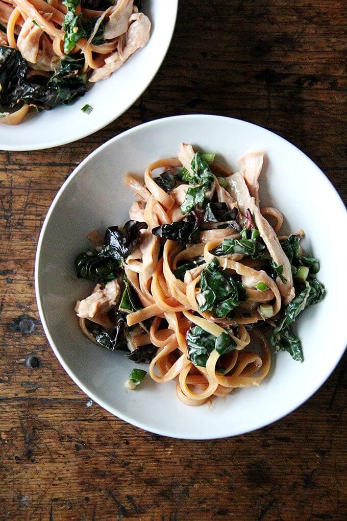 This is one of the easiest, tastiest, most genius recipes I've made in a long time: you drop a chicken breast into boiling water, cover the pan, then let it sit for 15 minutes off the heat. In the meantime, you make a sauce from all pantry ingredients — including both tahini and sesame oil for big sesame flavor — then you retrieve the chicken breast, cook sesame noodles in the now seasoned broth, and when they're done, you toss it all together. That's it! // alexandracooks.com a bowl of sesame noodles with swiss chard