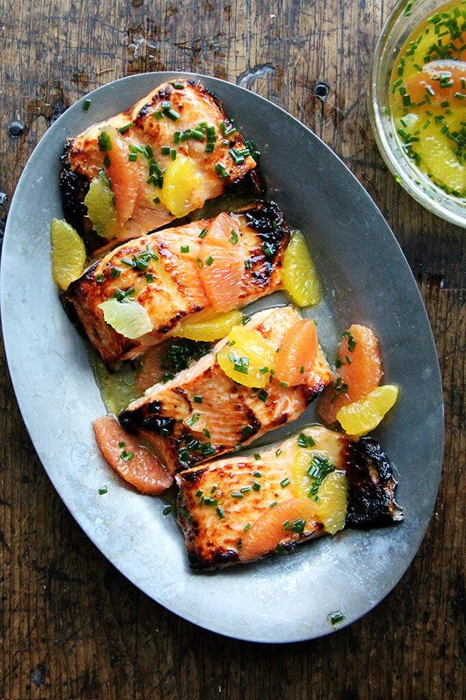 Arctic Char is mild and delicious. It's thin, so it cooks quickly. The sauce in this broiled lemon-honey arctic char is also a nice mix of citrus. I love using Cara Cara oranges for their sweet flavor and pretty hue. // alexandracooks.com A sizzle platter holding broiled arctic char dressed in a citrus sauce.