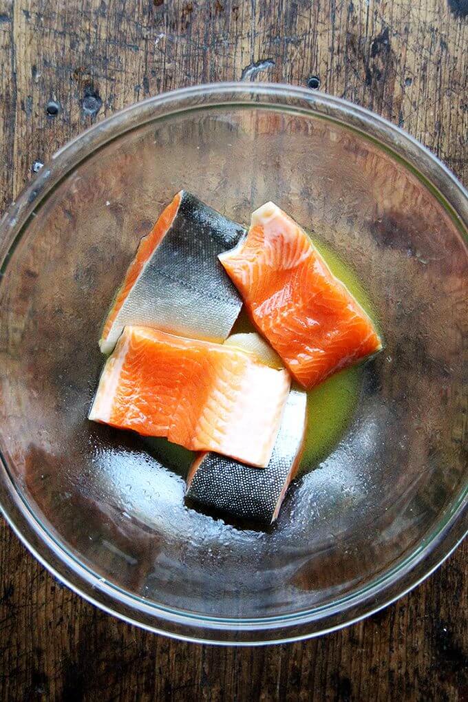 A bowl with arctic char marinating in honey, citrus juice, and olive oil.