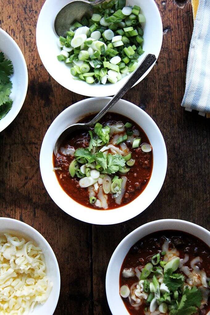 This super bowl menu includes weeknight chili which is my favorite, pared-down chili recipe. It comes together in about an hour and gets better by the day, so don't be afraid to make it ahead of time. // alexandracooks.com A few bowls of weeknight chili with assorted toppings.