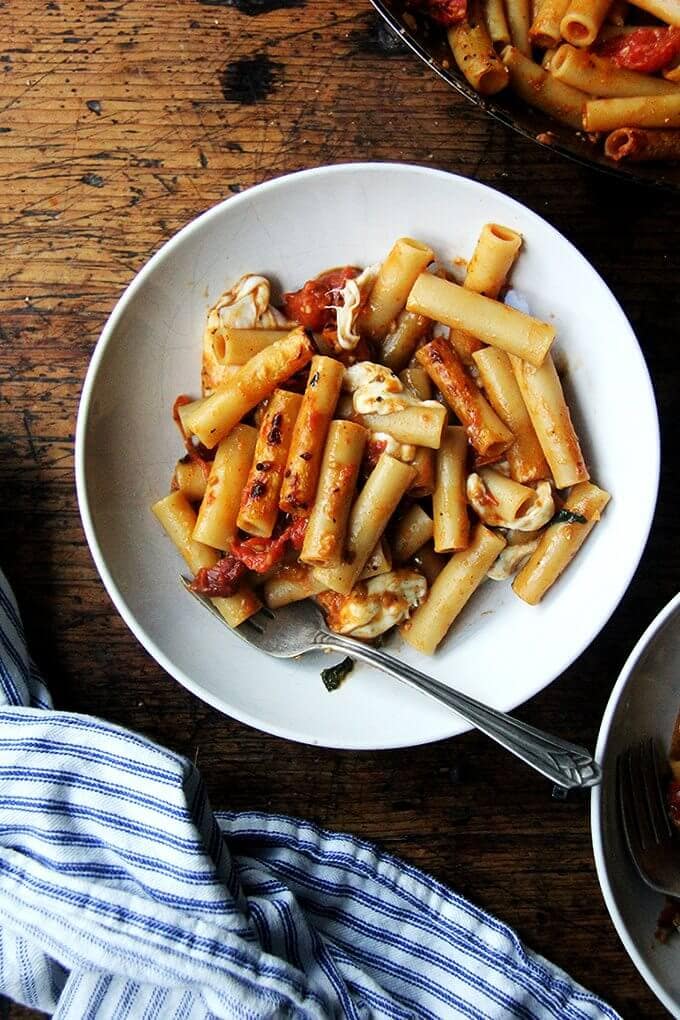 This one-pan baked ziti recipe has the added bonus of being a one-pot wonder: after you crush the tomatoes with a potato masher (or whisk or spoon), you add the dried pasta and water directly into the pan and simmer everything together until the pasta is cooked and the liquid has evaporated. In just about five minutes, your one-pan, no-fuss baked ziti is done: crisp noodles, melty cheese, bubbly sauce. // alexandracooks.com A bowl of the best one-pan baked ziti.