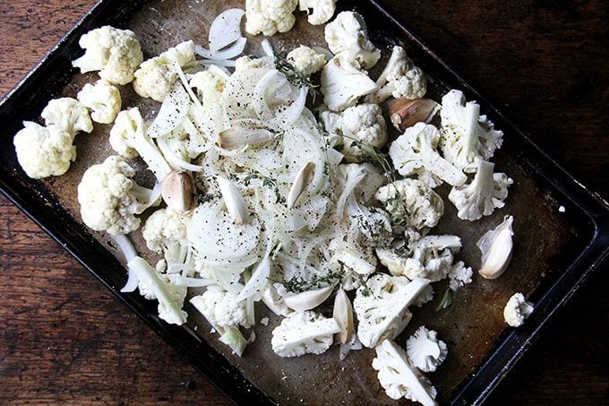 A sheet pan of cauliflower, onions, garlic, and thyme, not yet roasted.