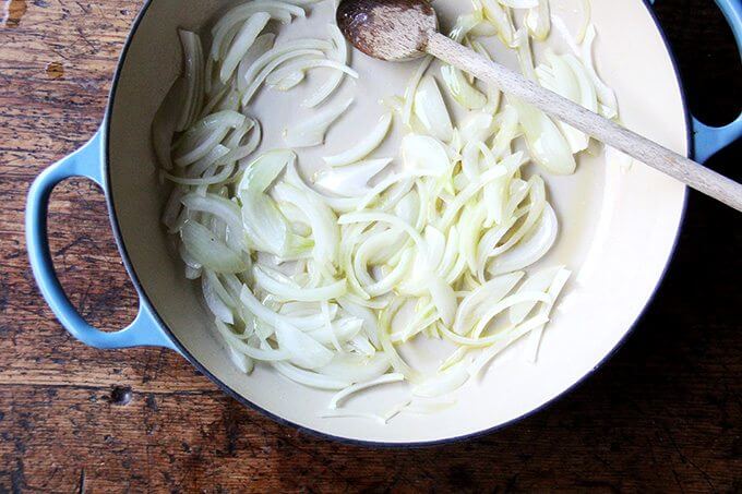A Le Creuset braiser filled with sautéed onions.