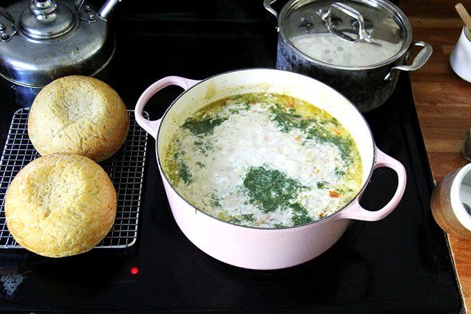 A large pot of vegetarian cabbage soup with heavy cream and dill added aside two loaves of homemade bread.