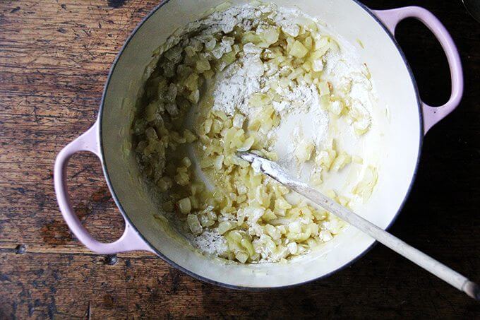 A large pot of onions sautéed in olive oil, with flour added.