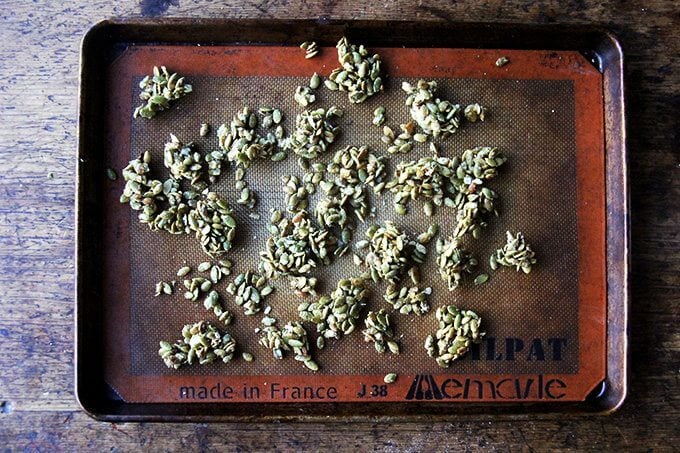 A sheet pan lined with a silpat topped with candied pumpkin seeds.