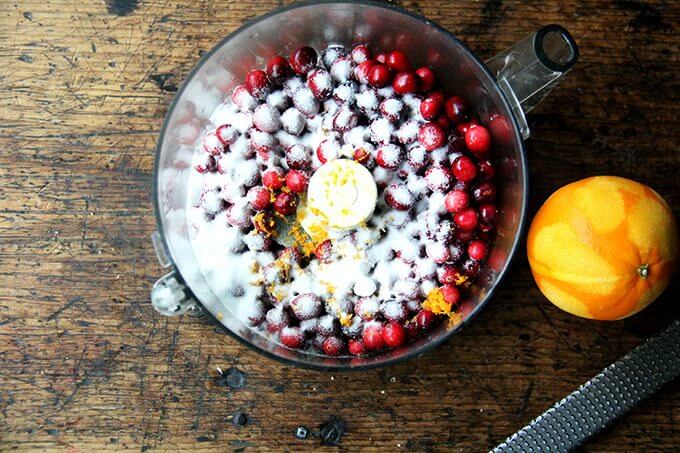 A food processor filled with cranberries, orange zest and sugar.
