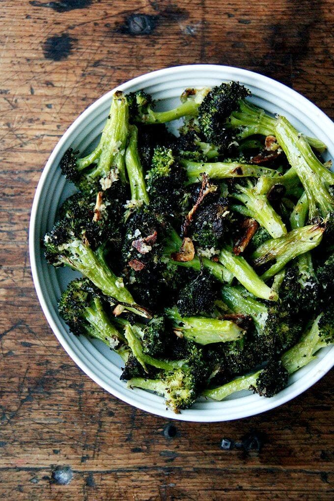 This roasted broccoli recipe is excellent and easy. I've made it three times in my portable Waring oven on two mini sheet pans in the past week because it just tastes so darn good right now—it's just what I'm craving after many weeks of indulging. // alexandracooks.com A bowl of Ina Garten's roasted broccoli florets with garlic, lemon, and parmesan.