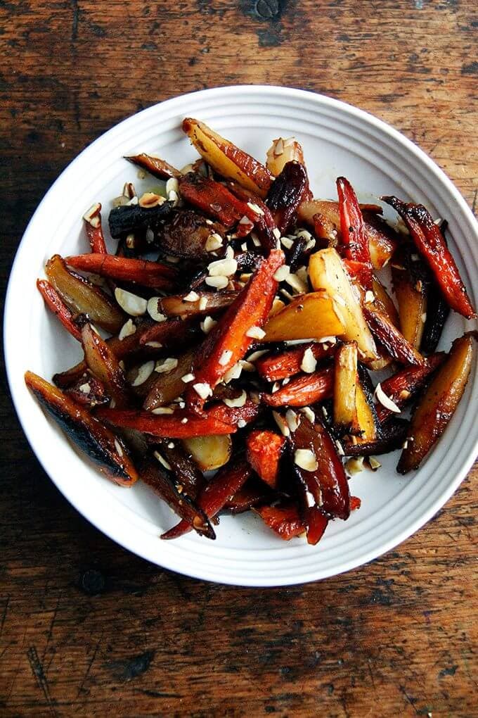 These burnt carrots with honey, black pepper, butter, and almonds are really twice-roasted carrots that bathe in vinegar after their first pass in the oven, then get dressed with butter and honey before their second. I set the finished dish on the kitchen table before running out to do errands, and while I was out, I received a text message from my husband that read: "I ate all of the carrots...sorry. They were so delicious." // alexandracooks.com A bowl of roasted carrots.