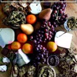 A cheese board filled with homemade three-seed crackers, cheese, candied pepitas, fruit, and quince paste.
