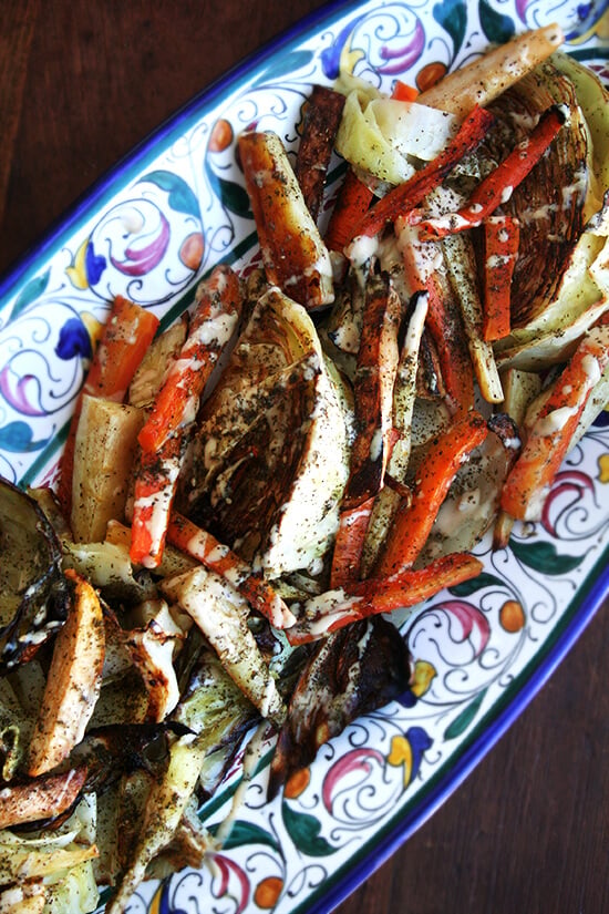 A platter of roasted vegetables with tahini sauce.