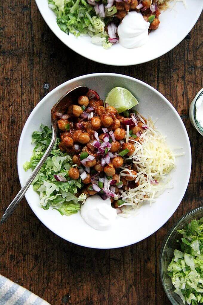 A bowl of chickpea tacos aside lettuce and cheese.