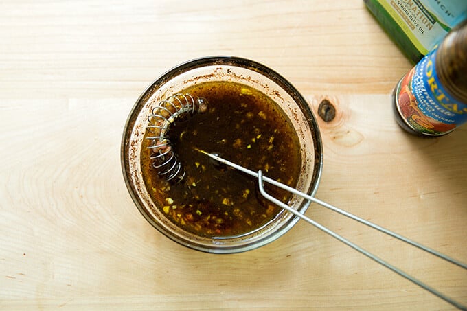 A bowl filled with fattoush salad dressing and a whisk.