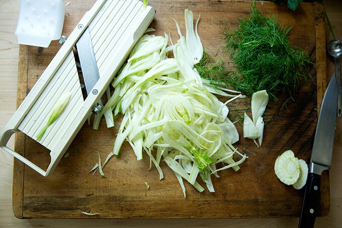 Cutting board with shaved, raw fennel and a Benriner mandoline.