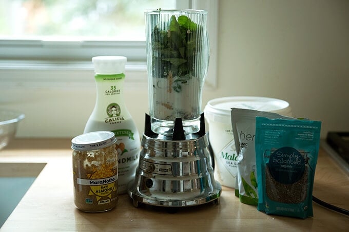 All of the ingredients for the green smoothie on the counter ready to be blended in the blender.