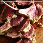 A board with sliced rack of lamb on top.