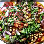 A plate of Israeli-spiced tomato and chickpea salad with cucumber-yogurt sauce.