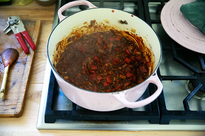 A large pot with vegetables cooking with chili powder and tomato paste.