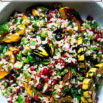 A white serving bowl filled with winter tabbouleh and roasted delicata squash slices.